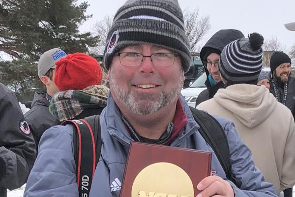 Ken Johnson displays the MIT men’s cross-country team’s first Division III NCAA National Championship trophy in 2022.