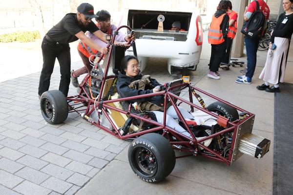 Students help the MIT Motorsports team push their car into Lobby 13 for the 2024 MIT Edgerton Center student showcase. 